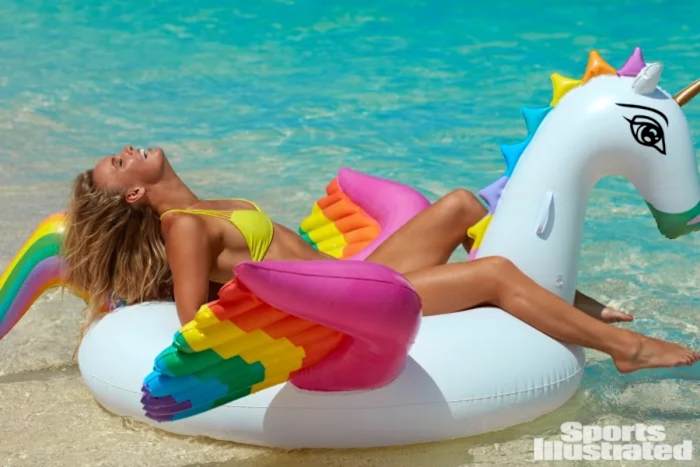Caroline Wozniacki sits on a white swan float with rainbow-colored wings in a neon green bikini.
